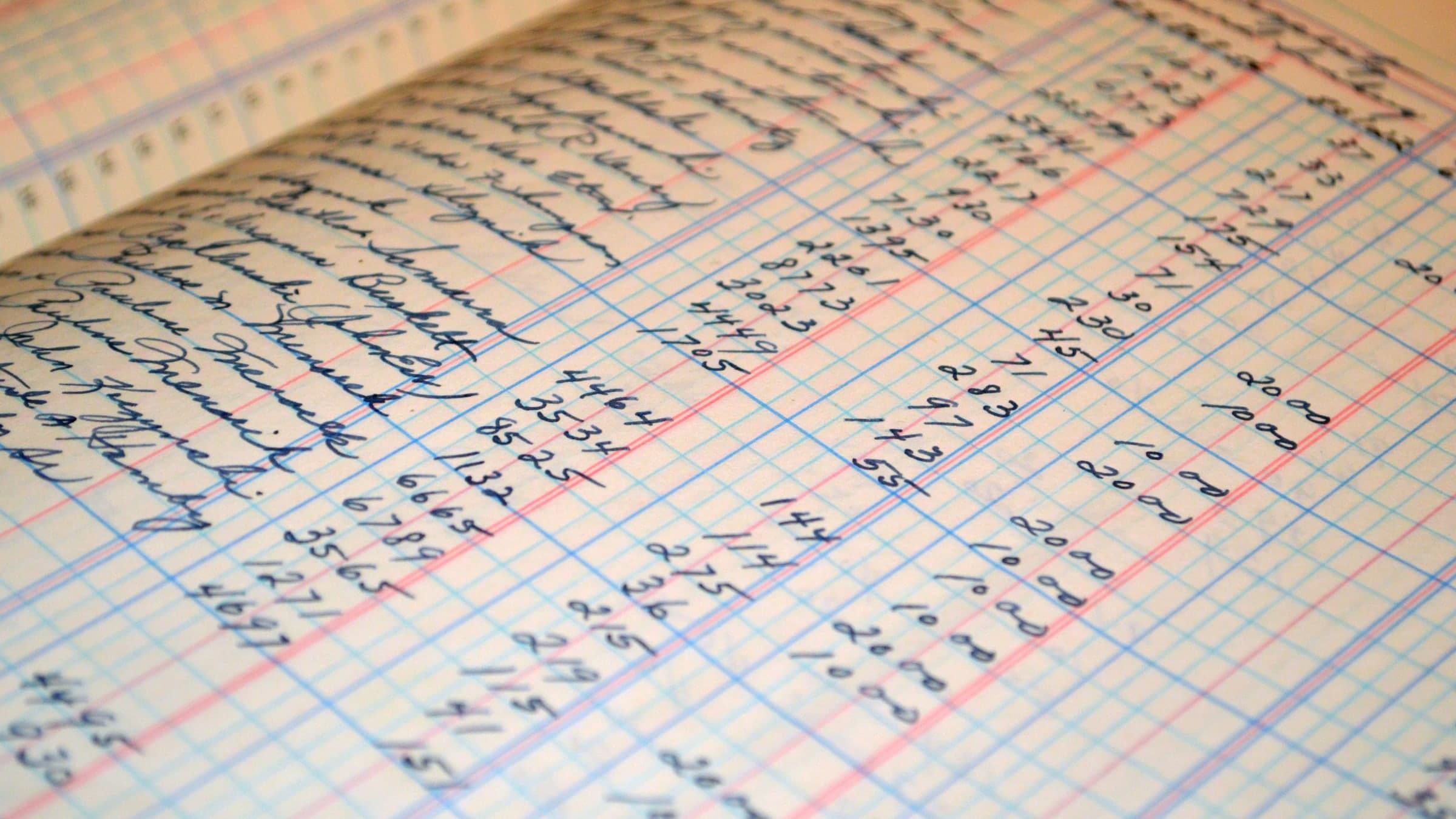 Pages d'un grand-livre manuscrit, colonnes réglées de bleu et de rouge, chiffres alignés à l'encre